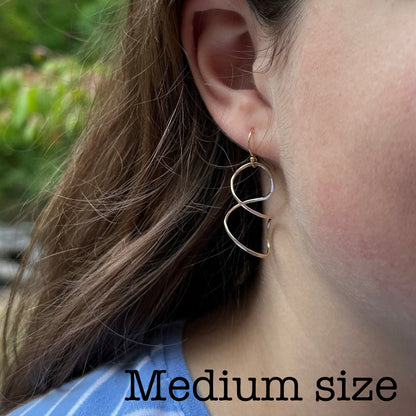 Twisty wire earring on model  for dressing up or down in sterling silver or 14kt gold filled in four sizes 1 to 2 inches long, available on french hook or leverback ear wires, simple classic handmade by hanni jewelry in harbor springs, michigan