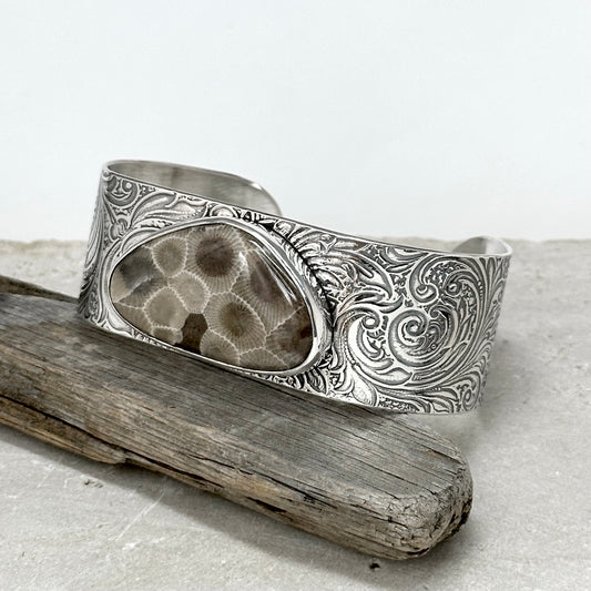 petoskey stone cuff bracelet with triangle shaped petoskey stone mounted on 1 inch sterling silver cuff bracelet with engraved scroll pattern on the silver. six inches long and slightly adjustable one size fits most handmade petoskey stone jewelry by Hanni jewelry, harbor springs, Michigan