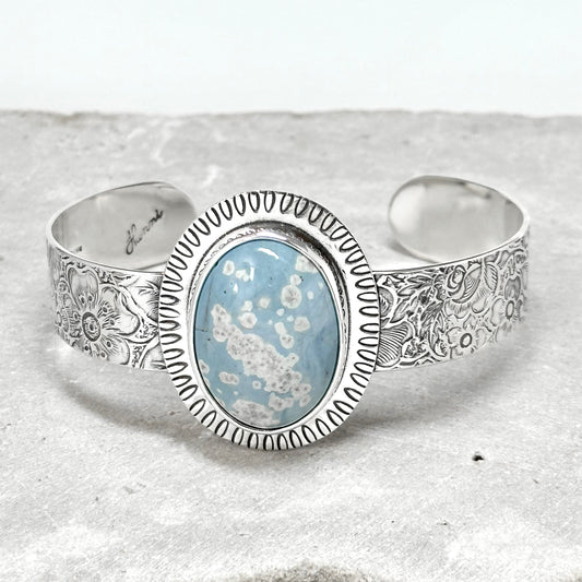 Leland blue bracelet sterling silver cuff bracelet set with large oval Leland blue stone light blue slag glass with stamped frame and vintage pattern 1/2 inch wide flower band, artist handmade silver jewelry by Hanni jewelry, harbor springs, Michigan
