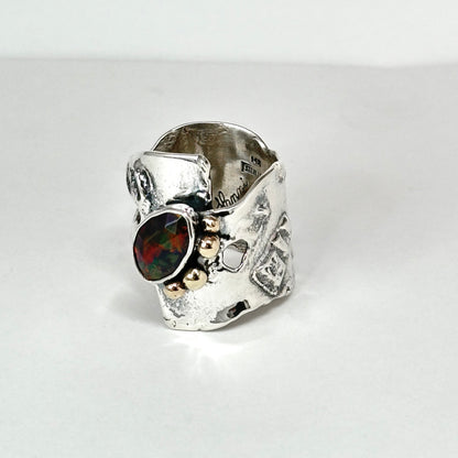 sterling silver and 14kt gold black opal ring with rustic flowing 3/4 inch wide band. a black opal is edged by 14kt gold balls on a rustic band in my flowing water style. handmade by Hanni jewelry, harbor springs michigan.